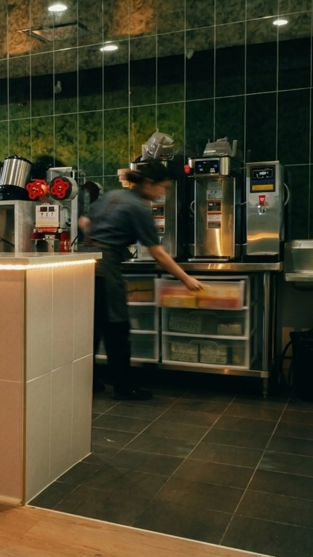A barista making drinks behind the Badger & Bloom Boba counter.